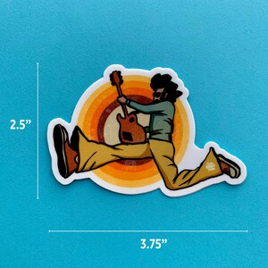 May include: A sticker of a cartoon person playing a guitar, jumping in the air, with a retro-style background of concentric circles in orange, yellow, and brown. The sticker is 3.75 inches wide and 2.5 inches tall.