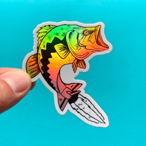 May include: A rainbow iridescent sticker of a bass fish jumping out of the water with a rocket engine attached to its tail.
