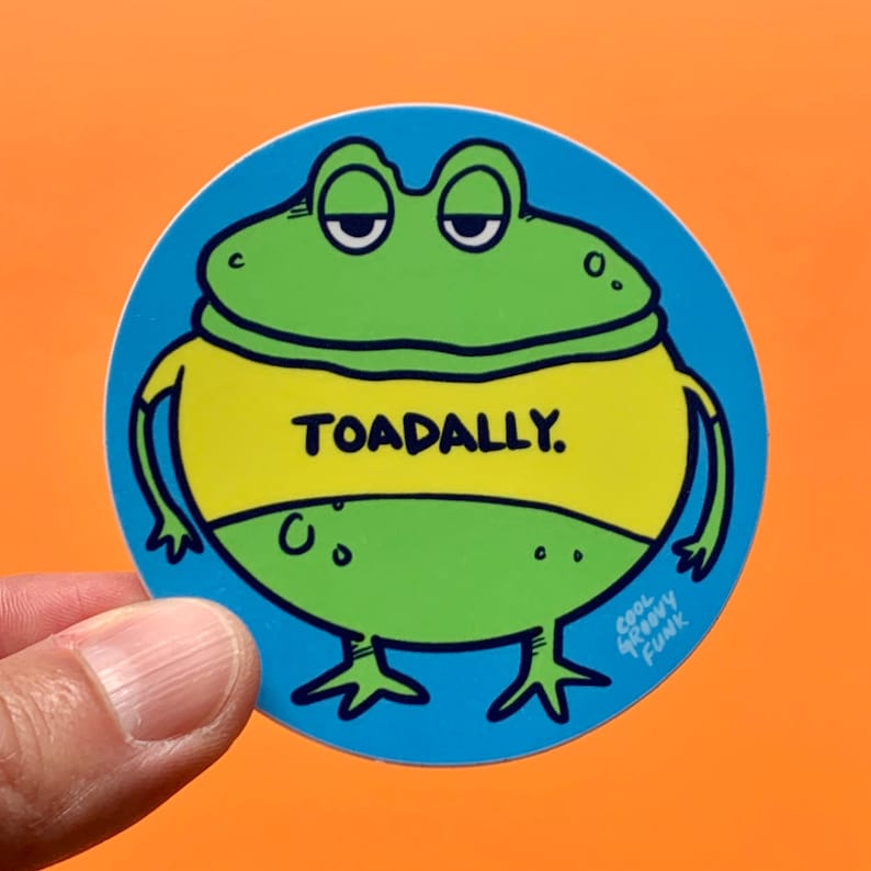 May include: A round sticker with a cartoon green frog wearing a yellow shirt that says "TOADALLY." The frog has a blue background and the text "Cool Greasy Funk" is in the bottom right corner.