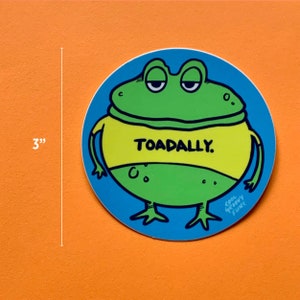 May include: A 3-inch round sticker featuring a cartoon green frog wearing a yellow shirt with the text "TOADALLY." The frog has a blue background with the text "COOL GROOVY FUNK" in the bottom right corner.