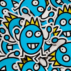 May include: A close-up of several blue and yellow cartoon monster stickers. The stickers have different expressions and features, including a crown, spikes, and teeth.