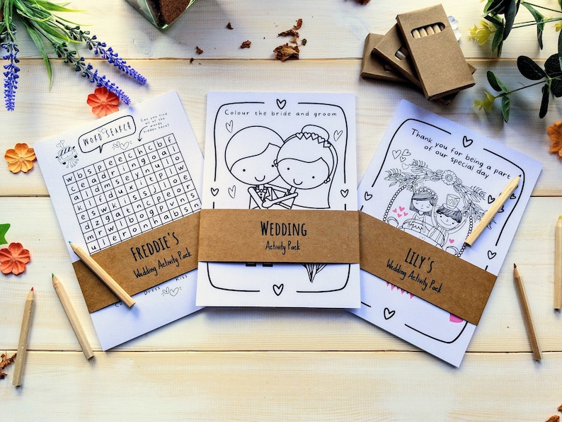 May include: Three wedding activity packs with brown paper covers and white paper inserts. The covers have the names Freddie, Wedding, and Lily's printed on them. The inserts have colouring pages and a word search puzzle.