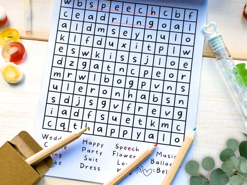 May include: A word search puzzle printed on white paper with a grid of black letters. The words speech and ring are circled in red ink. Below the grid, a list of words includes Wedding, Party, Suit, Dress, Speech, Flower, and Music. Two wooden pencils are placed across the bottom of the page.
