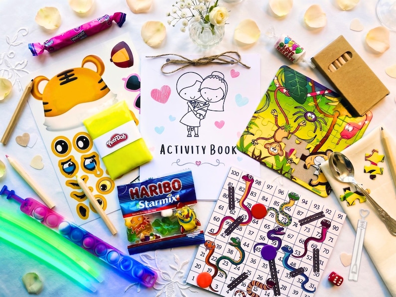May include: A collection of children's activity items including a wedding-themed activity book, a jungle-themed jigsaw puzzle, a snakes and ladders board game, a pack of Haribo Starmix, a yellow Play-Doh container, glow sticks, and wooden pencils.