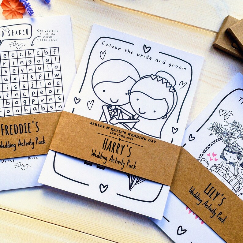 May include: Three wedding activity packs with colouring pages featuring a bride and groom, a couple under a floral arch, and a word search puzzle. The packs are labelled "Harry's", "Lily's", and "Freddie's" with the date "2nd June 2033" on Harry's pack.