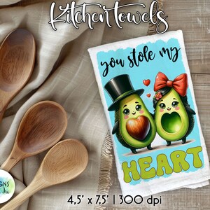 May include: A white kitchen towel with a blue background and the text "you stole my HEART" in a colorful font. Two cartoon avocados are depicted, one wearing a top hat and the other wearing a red bow. The towel measures 4.5 inches by 7.5 inches and has a 300 dpi resolution.