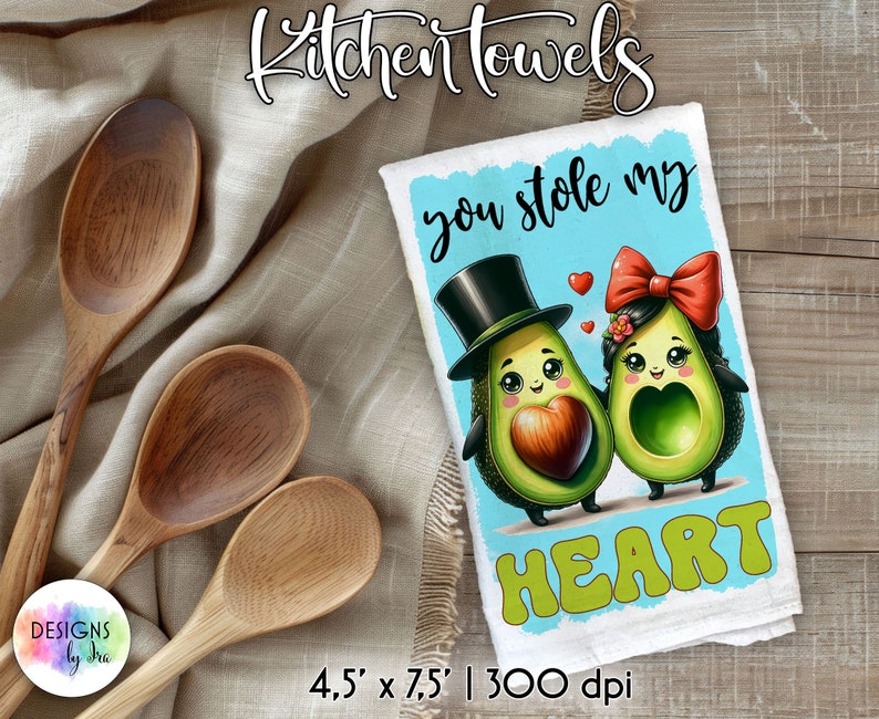 May include: A white kitchen towel with a blue background and the text "you stole my HEART" in a colorful font. Two cartoon avocados are depicted, one wearing a top hat and the other wearing a red bow. The towel measures 4.5 inches by 7.5 inches and has a 300 dpi resolution.
