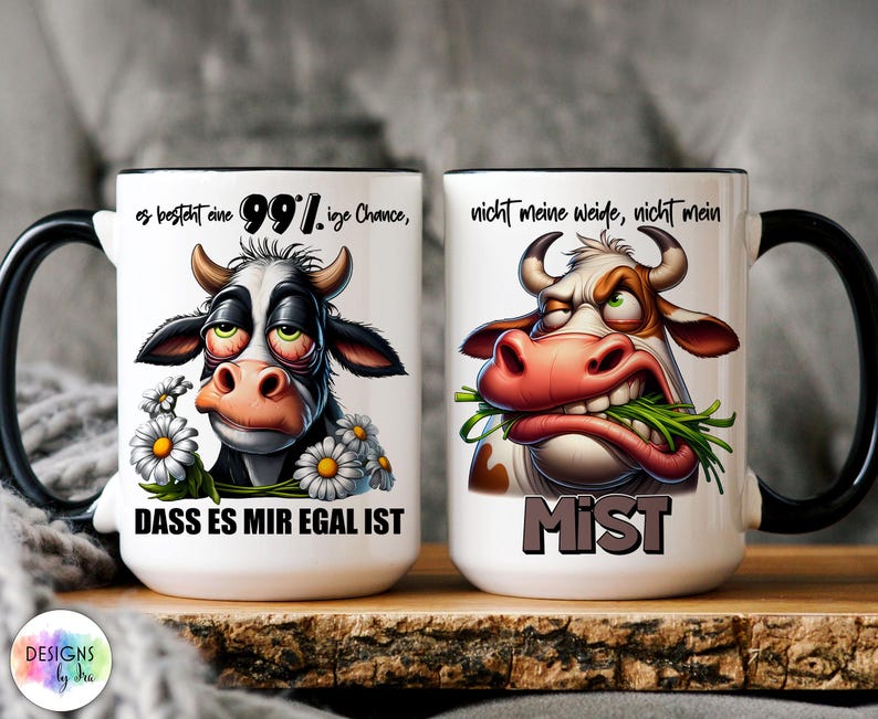 May include: Two white ceramic mugs with black handles and rims. Each mug features a cartoon cow illustration with text. One cow has daisies and the text reads "DASS ES MIR EGAL IST". The other cow has the text "MIST".