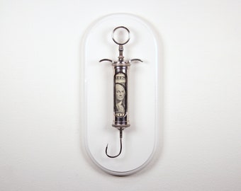 Hooked V3 - Satirical dollar bill/fishook/syringe sculpture from Nemo Gould