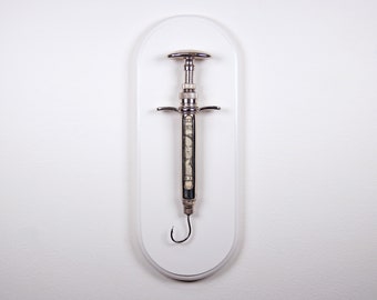 Hooked V1 - Satirical dollar bill/fishook/syringe sculpture from Nemo Gould