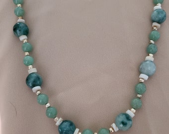 May include: A green and white beaded necklace with gold accents. The beads are round and have a smooth, polished finish.