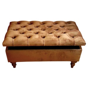 May include: A brown velvet storage ottoman with a tufted top and wooden legs. The top is open, revealing the storage space inside.