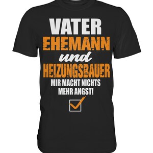 May include: Black t-shirt with orange text that reads "Vater Ehemann und Heizungsbauer Mir Macht Nichts Mehr Angst!" with a checkmark below the text.
