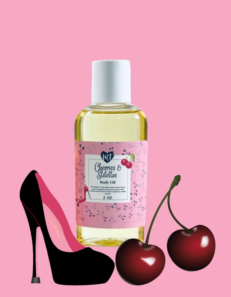 Op de afbeelding: Een heldere glazen fles body oil met een witte dop, met het label "Cherries & Stilettos". Het label is roze met kersen- en stiletto-afbeeldingen. Een zwarte en roze stiletto en twee kersen staan ook in de afbeelding. De fles bevat 59 ml olie.
