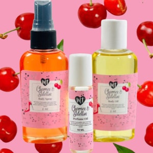 Op de afbeelding: Drie flessen geurproducten met roze etiketten en de tekst "Cherries & Stilettos". De flessen zijn gevuld met oranje en gele vloeistoffen. Rode kersen zijn verspreid rond de flessen tegen een roze achtergrond. De body spray fles is 59 ml.