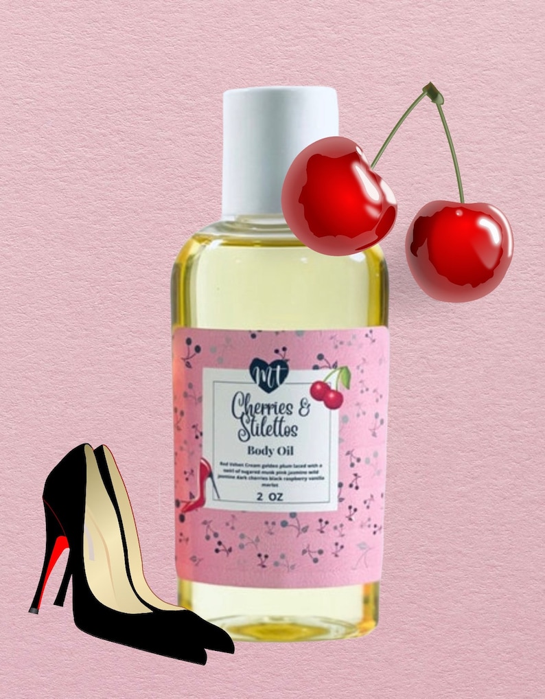 Op de afbeelding: Een flesje lichaamsolie met het label "Cherries & Stilettos". Het label is roze met een kersendesign. Een paar zwarte hoge hakken met rode zolen en twee rode kersen staan ook in de afbeelding. De fles bevat 59 ml olie.