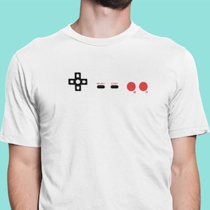 Mash those buttons. A nostalgic 8-bit game trip with the NES controller t-shirt. UNISEX