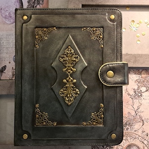 May include: A dark green leather-bound journal with gold accents and a decorative clasp. The journal has a vintage aesthetic and is perfect for writing, journaling, or sketching.
