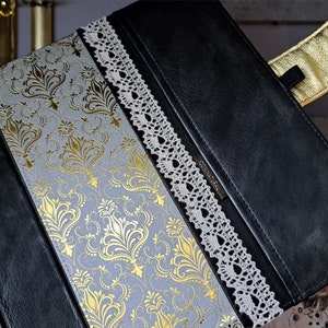 May include: A black leather journal with a gold and white damask pattern on the cover. The journal has a lace trim and the word "ORIGINAL" is embossed on the front.