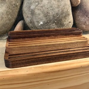 K&ouml;nnte beinhalten: Ein Holzorganizer mit drei Ebenen, jede Ebene mit mehreren Schlitzen. Der Organizer ist aus dunkelbraunem Holz gefertigt und hat eine nat&uuml;rliche Oberfl&auml;che.