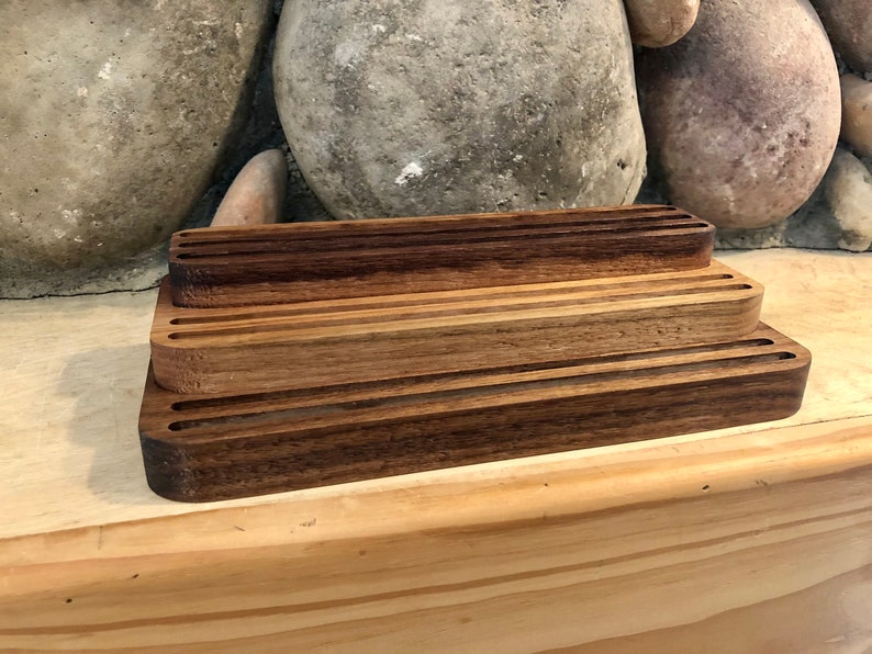 K&ouml;nnte beinhalten: Ein Holzorganizer mit drei Ebenen, jede Ebene mit mehreren Schlitzen. Der Organizer ist aus dunkelbraunem Holz gefertigt und hat eine nat&uuml;rliche Oberfl&auml;che.