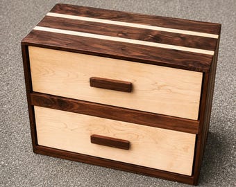 May include: A two-drawer wooden chest featuring a dark brown frame with two light beige drawer fronts. The top surface displays a dark brown wood grain with two light beige inlay stripes. Each drawer has a rectangular dark brown handle.