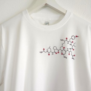 Camiseta con la molécula de oxitocina bordada a mano: un regalo inspirado en la ciencia.