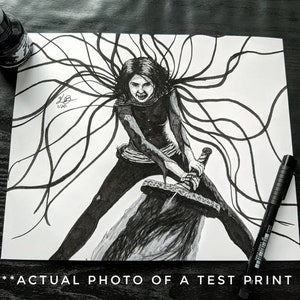 May include: Black and white illustration of a woman with long, flowing hair holding a sword. The woman has a determined expression on her face. The image is drawn in a detailed and realistic style.