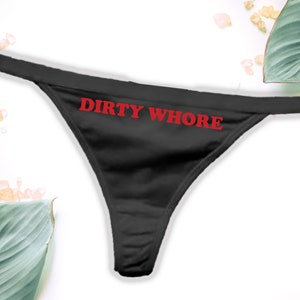 May include: Black lace thong underwear with the phrase "DIRTY WHORE" printed in red.