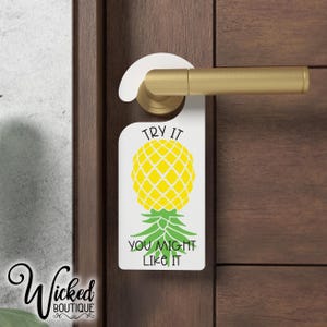 May include: White door hanger with a pineapple graphic and the text "Try it you might like it".