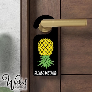 Könnte beinhalten: Schwarzer Türhänger mit einem Ananas-Motiv und dem Text "Please Disturb".