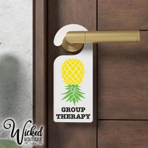 May include: White door hanger with a pineapple graphic and the text "Group Therapy".