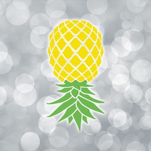 May include: A yellow pineapple with green leaves on a white and gray background with a bokeh effect.