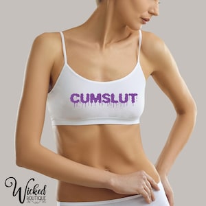 以下が含まれることがあります： 紫色の滴るテキストが「CUMSLUT」と書いてある白いスポーツブラ