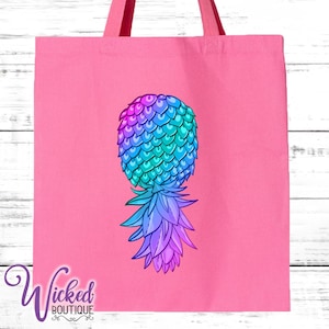 May include: A pink tote bag with a colorful pineapple design. The pineapple is a gradient of blue, green, and purple.