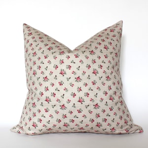 May include: A beige pillow with a small pink rose pattern. The pillow is made of a soft, linen-like fabric.