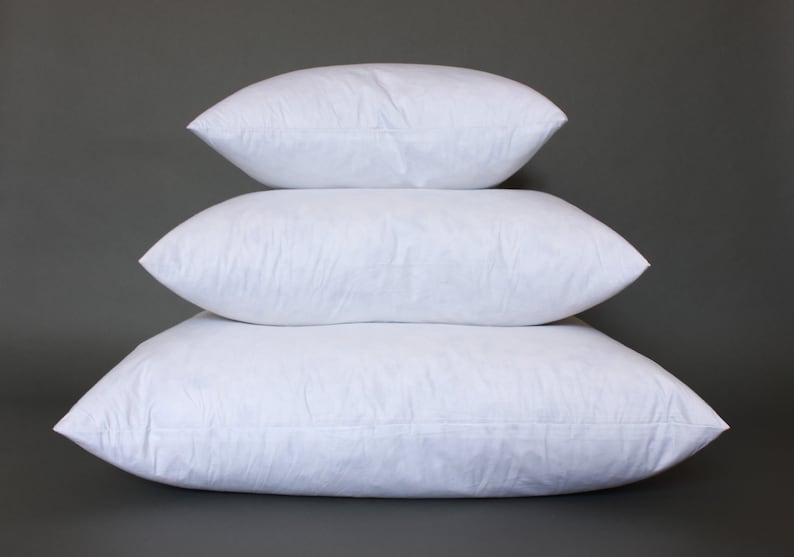 Puede incluir: Tres rellenos de almohada blancos apilados uno encima del otro sobre un fondo gris. Las almohadas est&aacute;n hechas de un material suave y esponjoso, perfectas para agregar comodidad y soporte a cualquier cama o sof&aacute;.