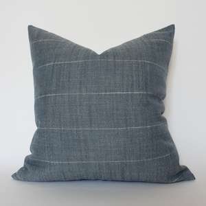 May include: A blue cushion with a subtle white stripe pattern. The cushion is made of a soft, textured fabric.
