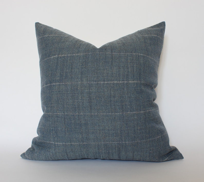 May include: A blue cushion with a subtle white stripe pattern. The cushion is made of a soft, textured fabric.