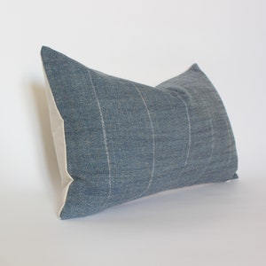 May include: A blue and white striped throw pillow with a textured fabric. The pillow is rectangular and has a white border.