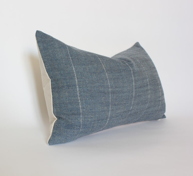 May include: A blue and white striped throw pillow with a textured fabric. The pillow is rectangular and has a white border.