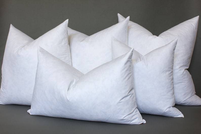 Puede incluir: Un grupo de seis almohadas blancas rellenas de plum&oacute;n dispuestas en forma de pir&aacute;mide. Las almohadas son todas del mismo tama&ntilde;o y forma, y todas est&aacute;n hechas de una tela blanca suave.