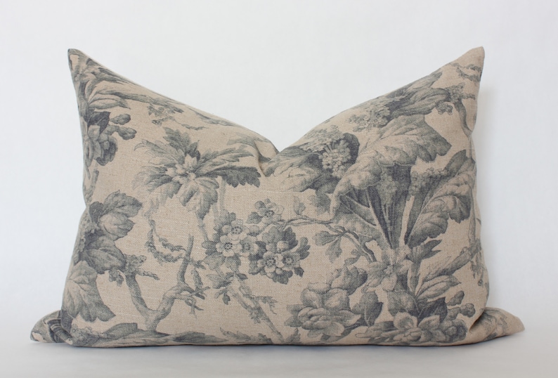 May include: A decorative pillow with a floral pattern in shades of gray and beige. The pillow is made of a linen fabric and has a subtle texture.