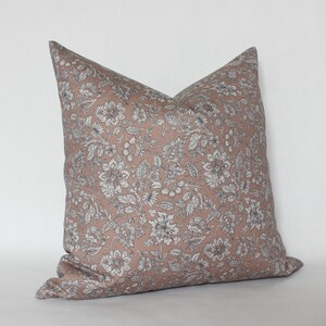 May include: A blush pink pillow with a white and gray floral pattern. The pillow is made of a soft, comfortable fabric and has a subtle sheen.