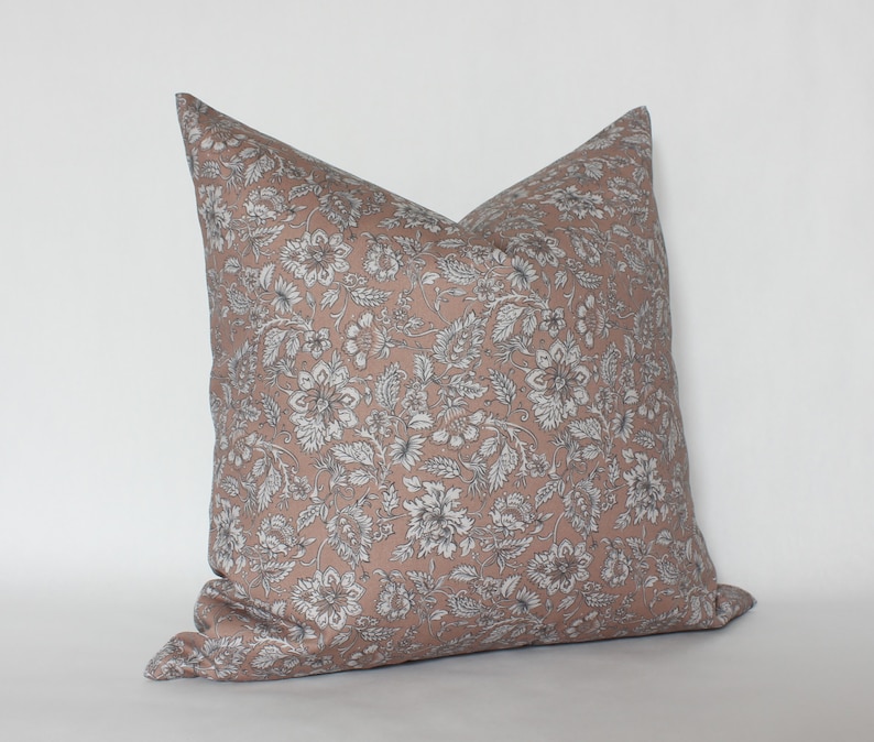 May include: A blush pink pillow with a white and gray floral pattern. The pillow is made of a soft, comfortable fabric and has a subtle sheen.