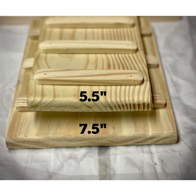 Placed on a white cloth, these pressure treated ramps are stacked from largest to smallest starting with a 7.5 inch wide ramp 5.5 inch wide ramp they both have rungs spaced 3 inches apart and sanded smooth to the touch the color is a yellow natural