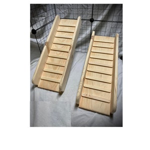 May include: Two wooden ramps with steps for small animals. The ramps are made of natural wood and have a light brown color.