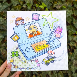 May include: Illustration of a light blue handheld gaming console with a dog on the screen. The image includes cartoon characters, a stylus, and the text "You won Best in Show!" A decorative charm bracelet is also featured.