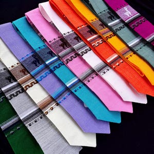 May include: A collection of ten neckties arranged in a diagonal fan pattern. Each tie features a solid color fabric, including green, gray, white, lavender, turquoise, pink, light pink, orange, yellow, and magenta, with a woven patterned band.