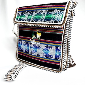 May include: A black and brown woven shoulder bag with a colorful geometric pattern and a small embroidered llama. The bag has a long strap and a small handle.